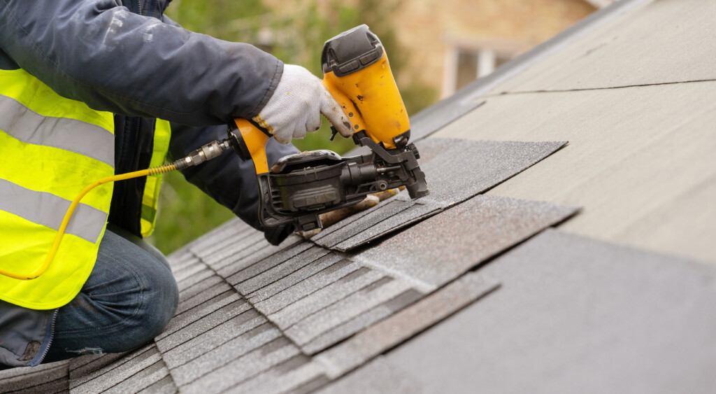 Contractor installing asphalt shingles on a roofing structure