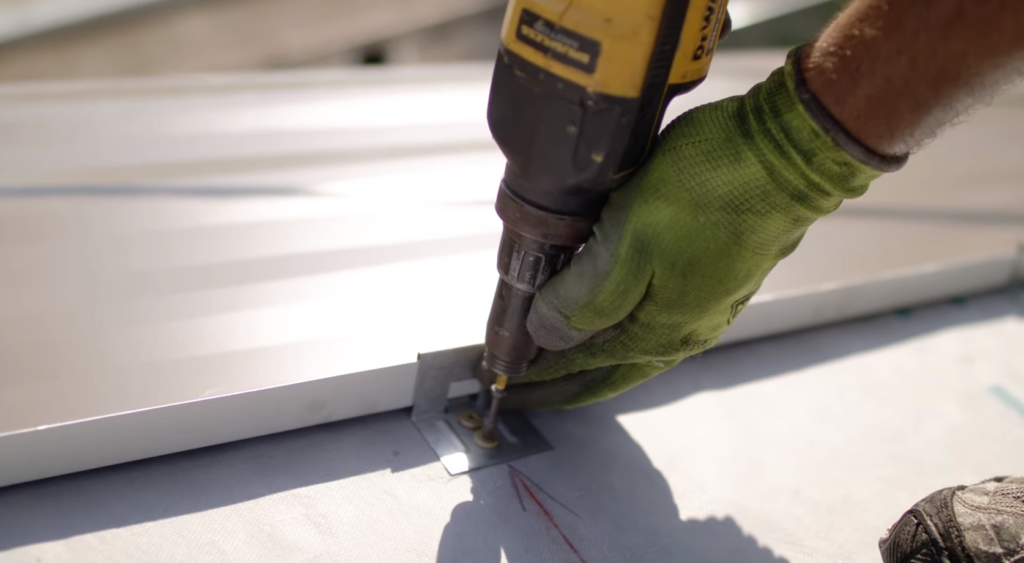 A metal roofing contractor installing a clip on a standing seam metal roof system