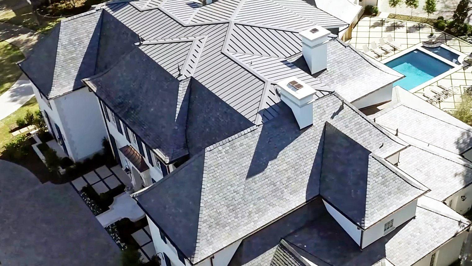 Aerial view of a multi-faceted, large home with a metal roof