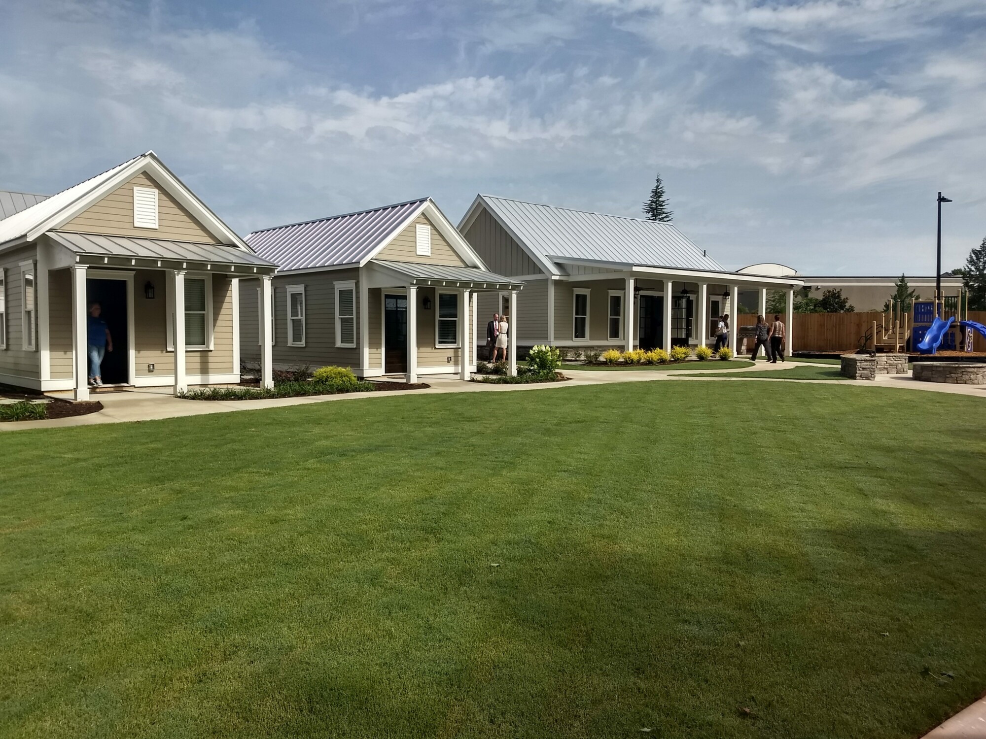 Three small homes with metal roofs in a neighborhood community 