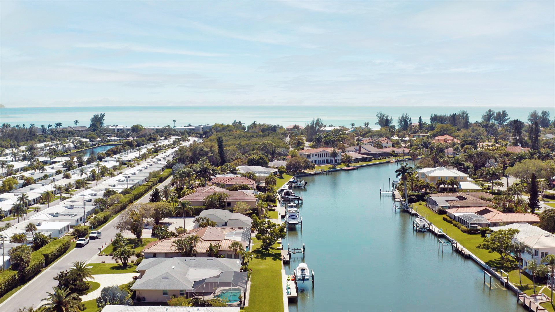 Coastal homes with metal roofs situated alongside a still waterway with an ocean in the background