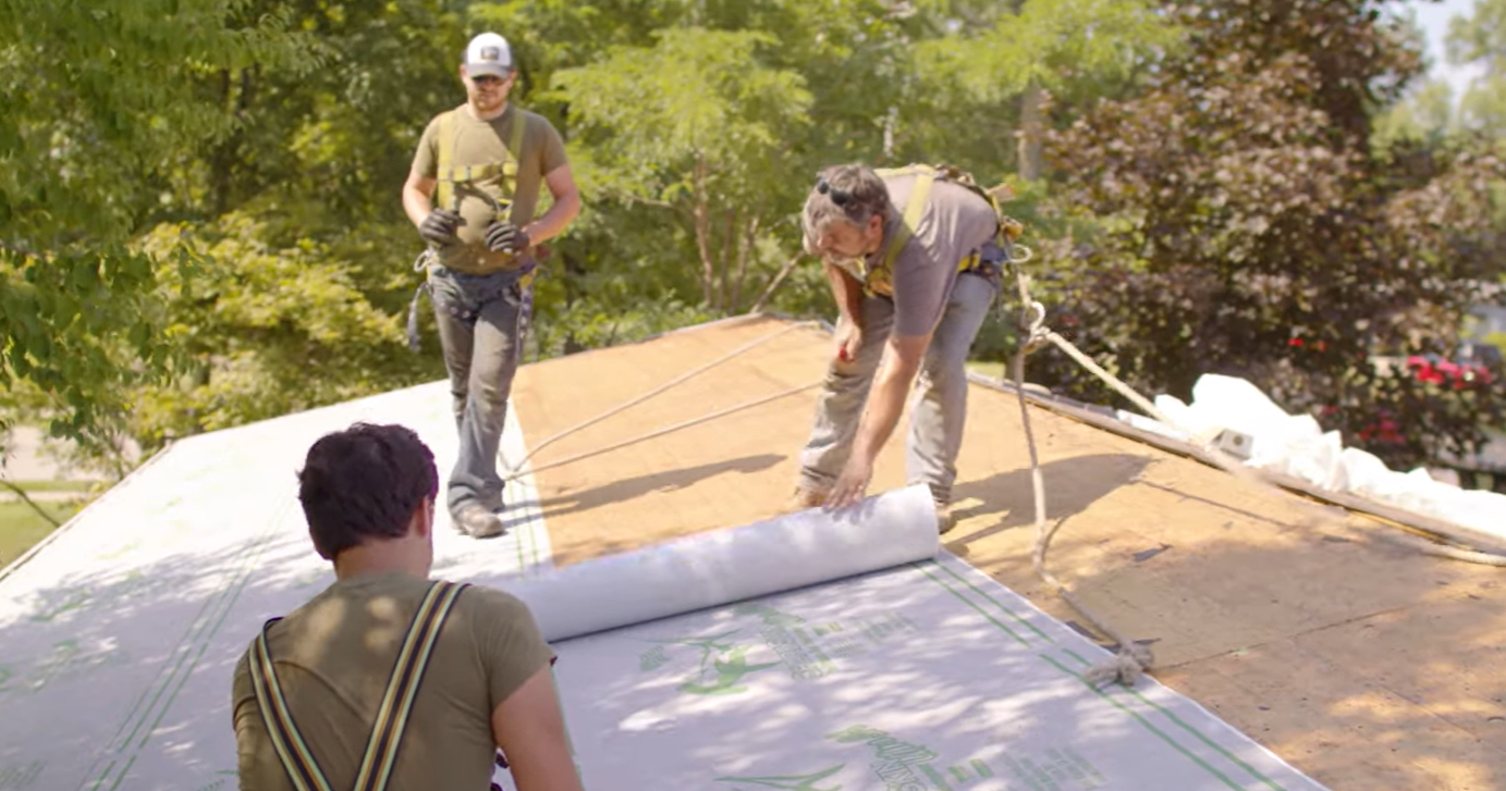 Contractors unrolling Sharkskin Ultra SA on a roof 