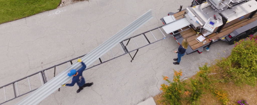 Aerial view of a contractor taking a metal panel from a rollforming machine 